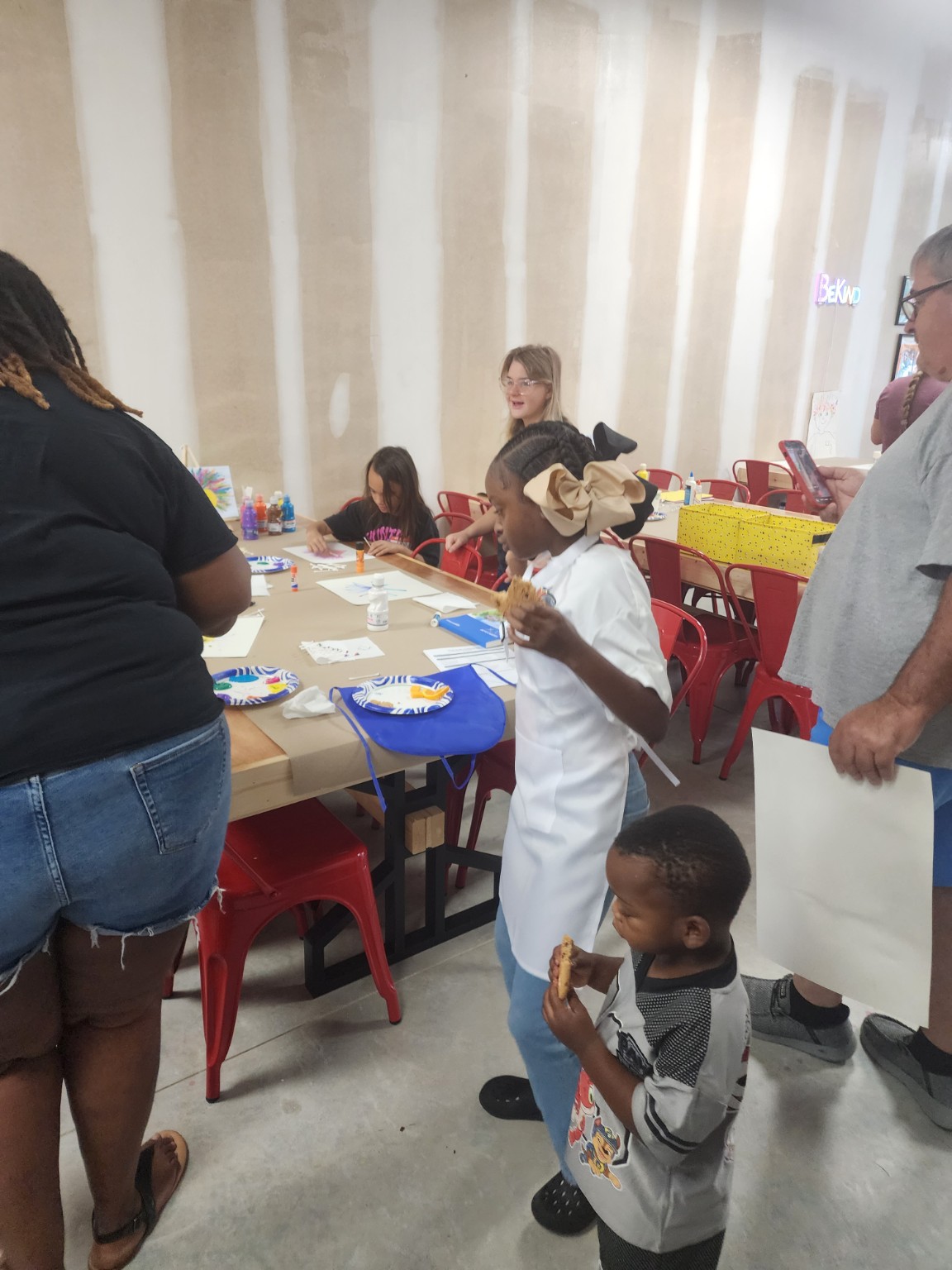 Children and adults gathering around craft tables during opening day