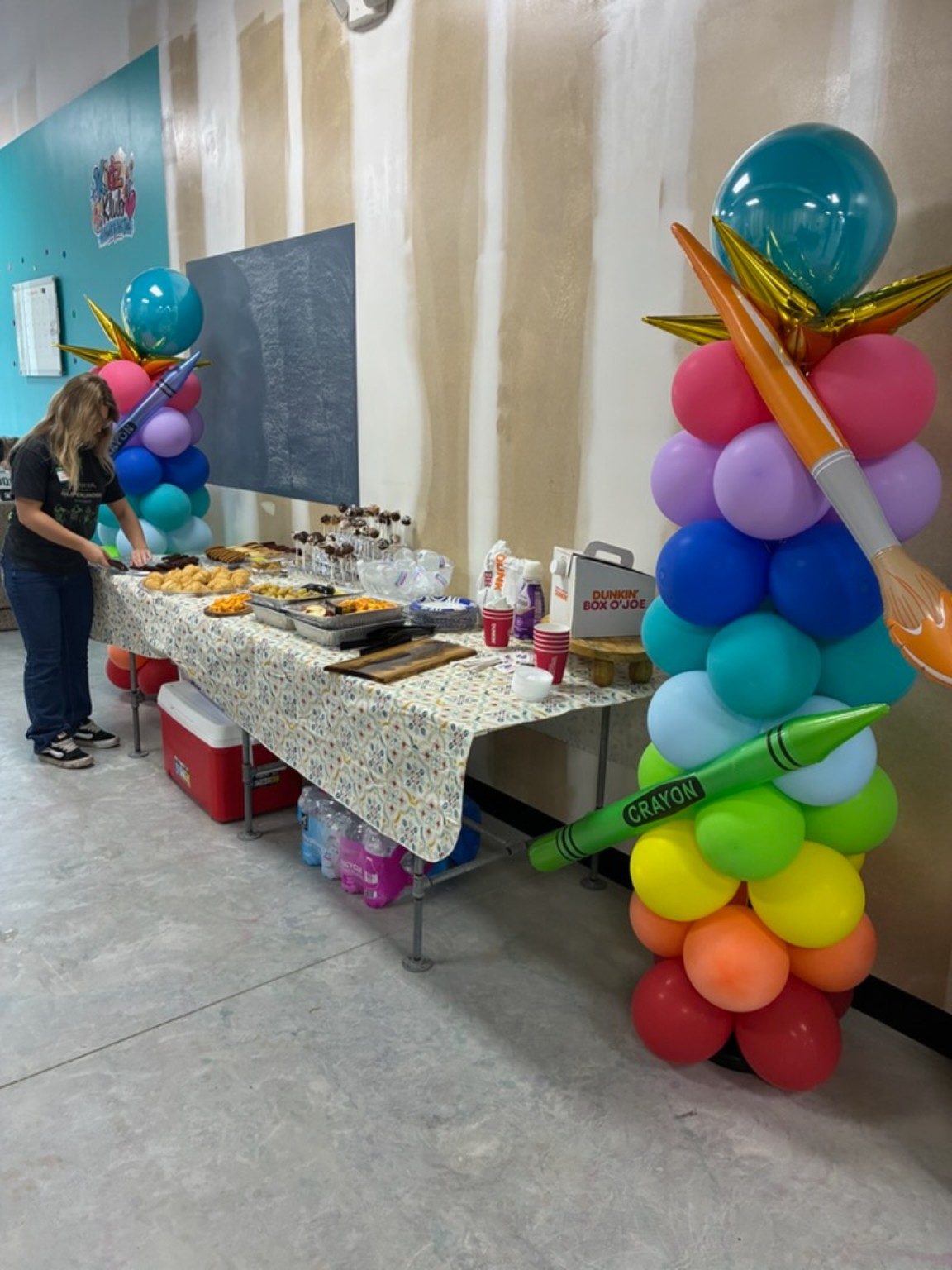 Refreshments and coffee beside rainbow balloon columns decorated with giant crayons