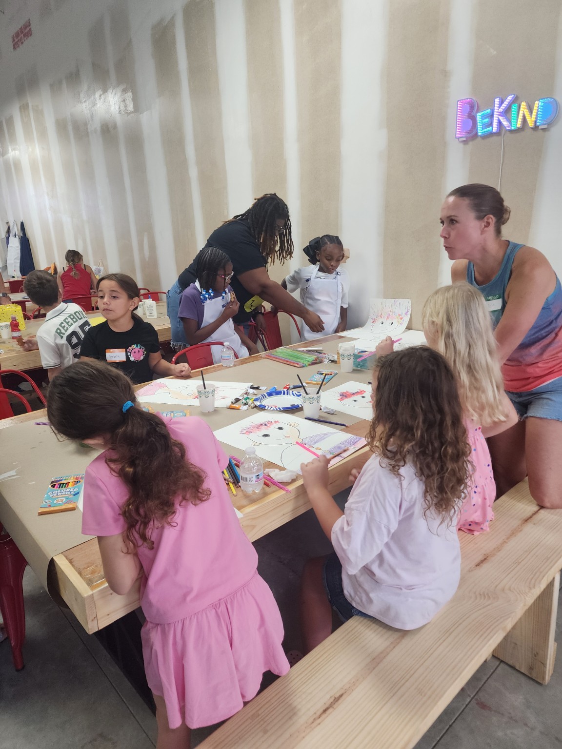 Families gathered around a long crafting table in the studio